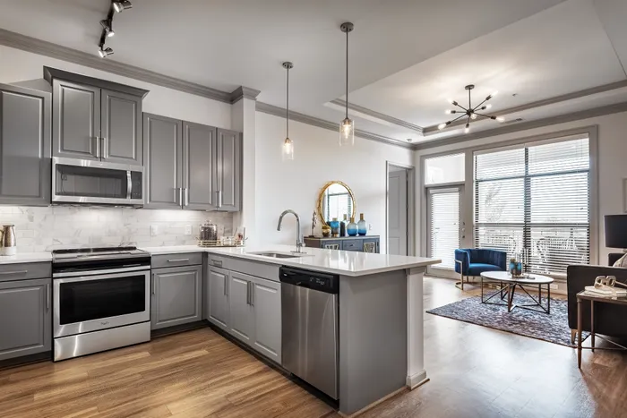 Bright and modern open-concept kitchen and living room with high-end finishes and stylish decor at The Hendry in Garland, TX.