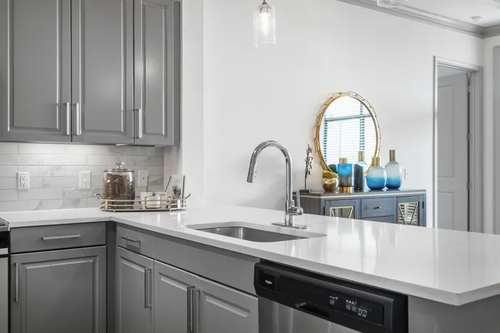 Modern kitchen with a sleek sink, gray cabinetry, and elegant decor at The Hendry Apartments in Garland, TX.