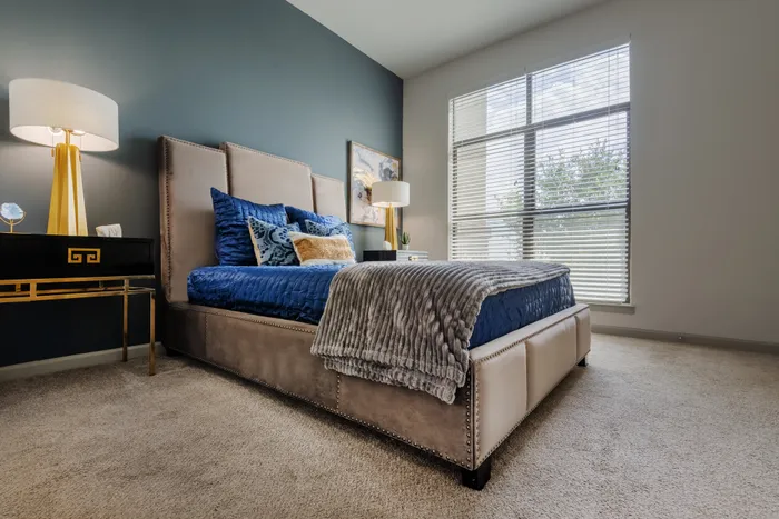 Sophisticated bedroom with a dark accent wall and luxurious bedding at The Hendry Apartments, Garland, TX.
