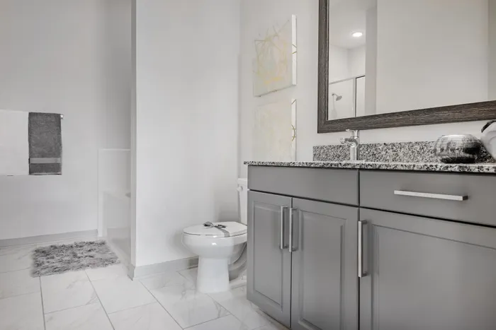 Spa-inspired bathroom with sleek gray vanity, granite countertops, and modern decor at The Hendry in Garland, TX.