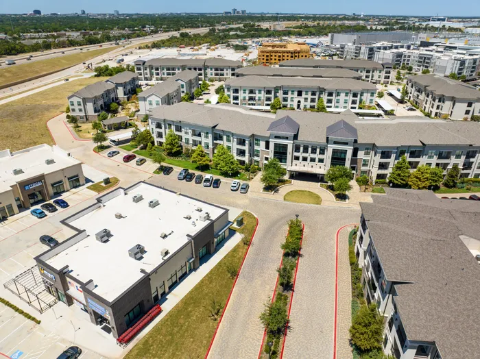 Aerial view of The Hendry Apartments with surrounding shops and greenery in Garland, TX.