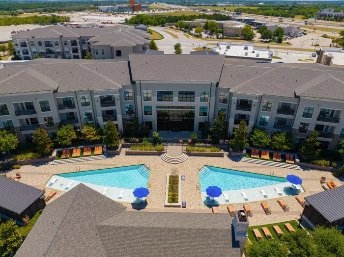 Resort-style swimming pool surrounded by lush landscaping at The Hendry Apartments, Garland, TX.
