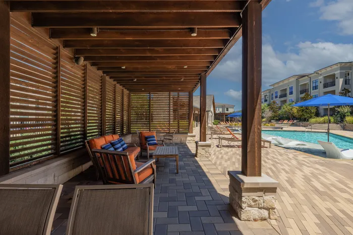 Shaded outdoor seating area with a poolside view at The Hendry Apartments, Garland, TX.