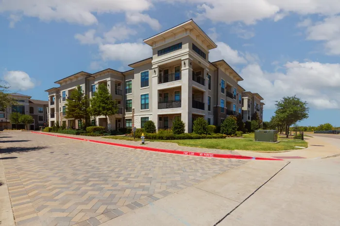 Beautiful exterior of The Hendry Apartments with manicured landscaping in Garland, TX.