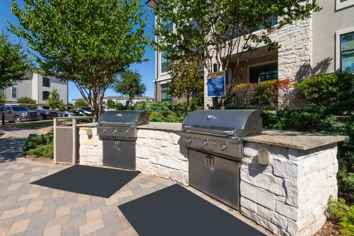 Outdoor grilling station with modern grills and shaded seating at The Hendry Apartments, Garland, TX.