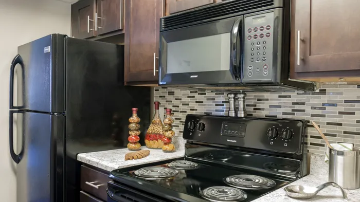 Contemporary kitchen in Carrollton, TX apartment with black appliances and stylish backsplash.