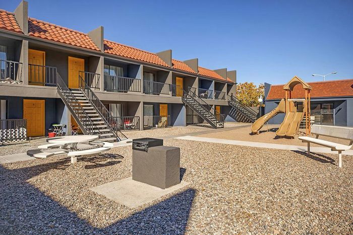 Outdoor playground and shaded sitting area at Las Brisas Apartments in Albuquerque, NM.