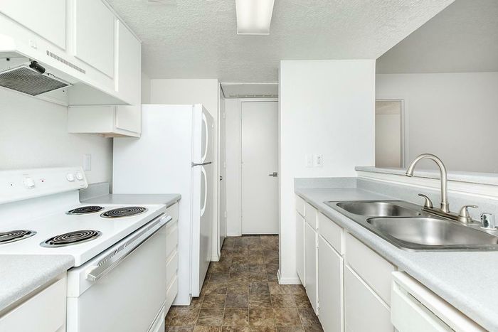 Well-lit kitchen with durable countertops, electric stove, and white cabinetry at Lifestyles at Renaissance Apartments.
