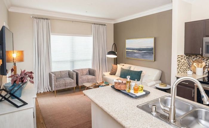 kitchen bar overlooking a cozy living room with hardwood floors, a rug, chairs, couch, and a painting
