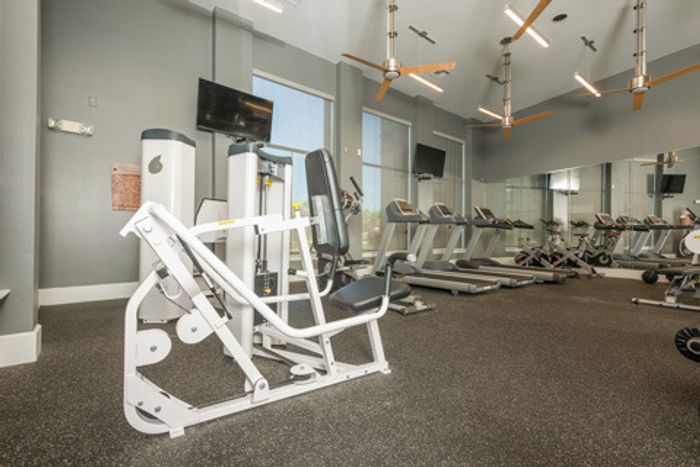 fitness center with workout machines and televisions