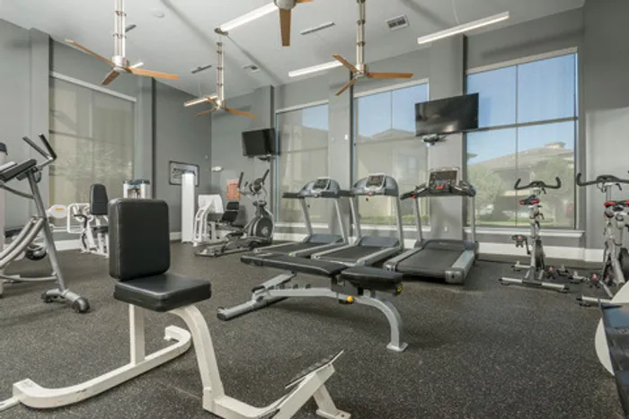 fitness center with workout machines and televisions