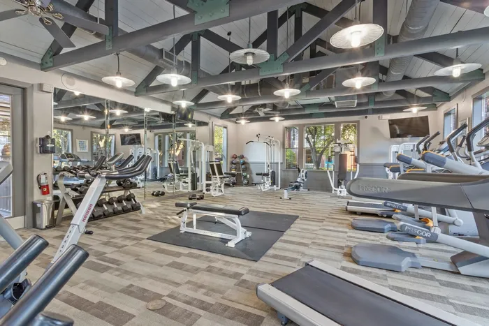 fitness center filled with bright lighting, exercise equipment, and weights