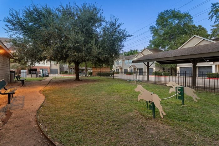 dog park with grass, a walking path, and comfortable benches