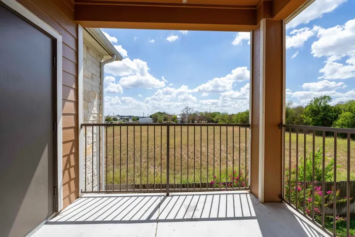 Private balcony with scenic views of Seguin, TX apartment community and parking area.