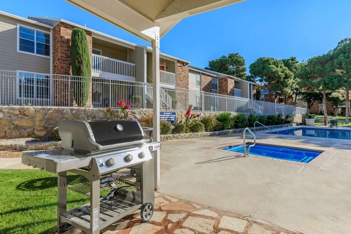 Outdoor grilling area by the pool at Whispering Pines Apartments in El Paso, TX, perfect for gatherings.