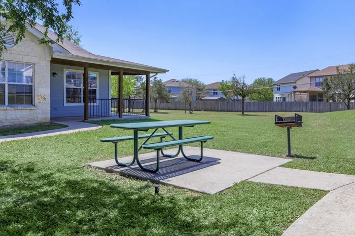 Picnic tables and shaded seating at Crescent Village outdoor area in Elgin, TX
