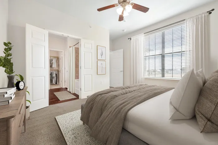 Master bedroom in Seguin, TX apartment with neutral decor, large windows, and walk-in closet.