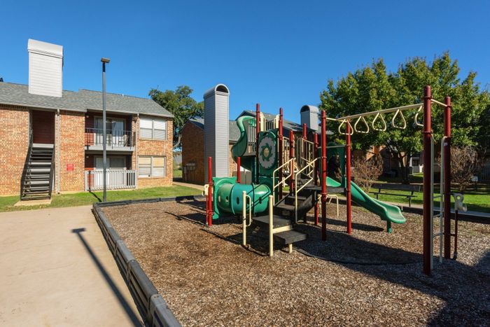 Playground in a Carrollton, TX apartment community with modern equipment and open green space.