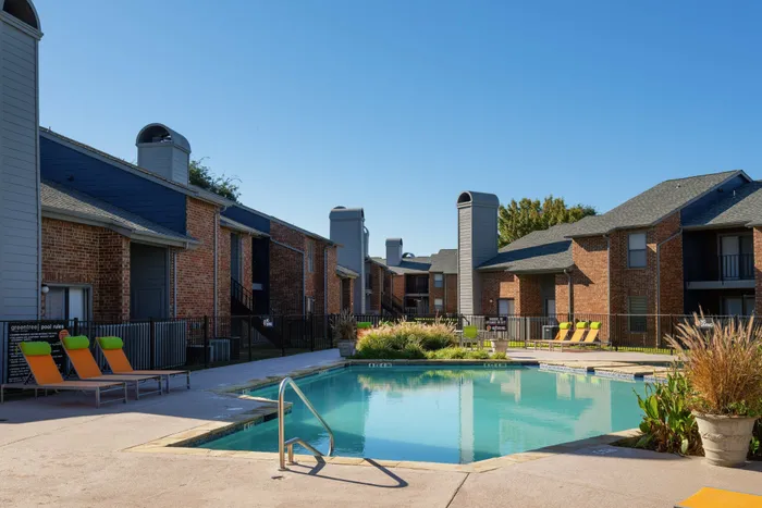 Resort-style swimming pool with lounge chairs and landscaping at a Carrollton, TX apartment complex.