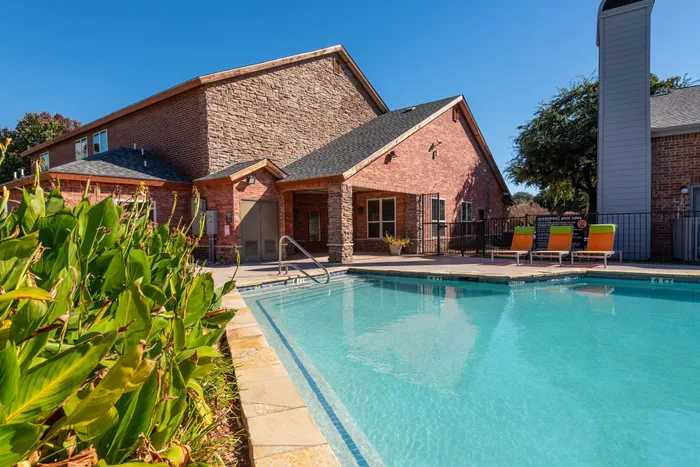 Resort-style swimming pool with lounge chairs and landscaping at a Carrollton, TX apartment complex.