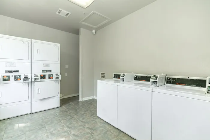a room washing machine and dryers atop a tiled floor
