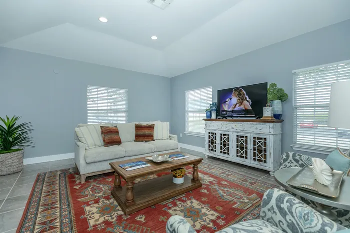 Spacious clubhouse with a comfortable sofa, beautiful area rug, and entertainment center at Portside Villas, Ingleside, TX