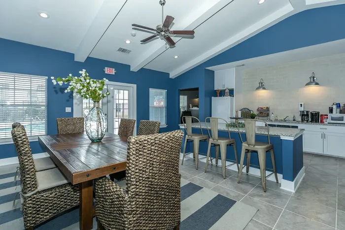 Spacious dining and kitchen area with wooden dining table, bar stools, and modern appliances at Portside Villas in Ingleside, TX