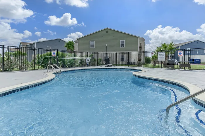 Sparkling lounge pool surrounded by comfortable seating and lush greenery at Portside Villas, Ingleside, TX
