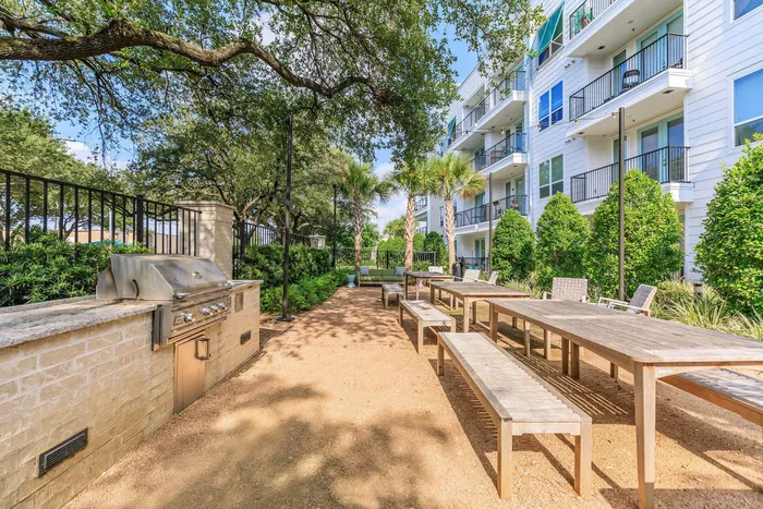 community picnic and grilling area, tables and benches atop a loose dirt surface