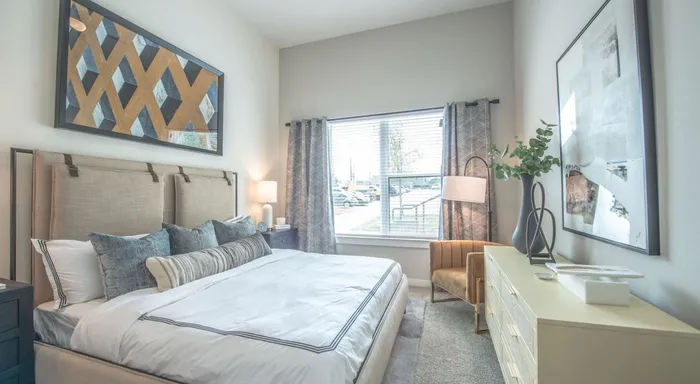 a cozy bedroom with a soft-looking bed, plush wall-to-wall carpeting, and a large window