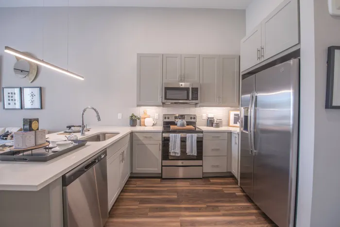 modern kitchen with hardwood floors, stainless steel appliances, white cabinets, and white countertop