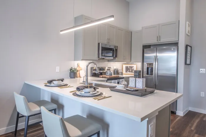 modern kitchen with hardwood floors, stainless steel appliances, white cabinets, and white countertop