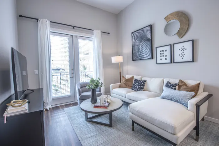 spacious room with white walls, a large window, white couch, a rug, and other living room furniture