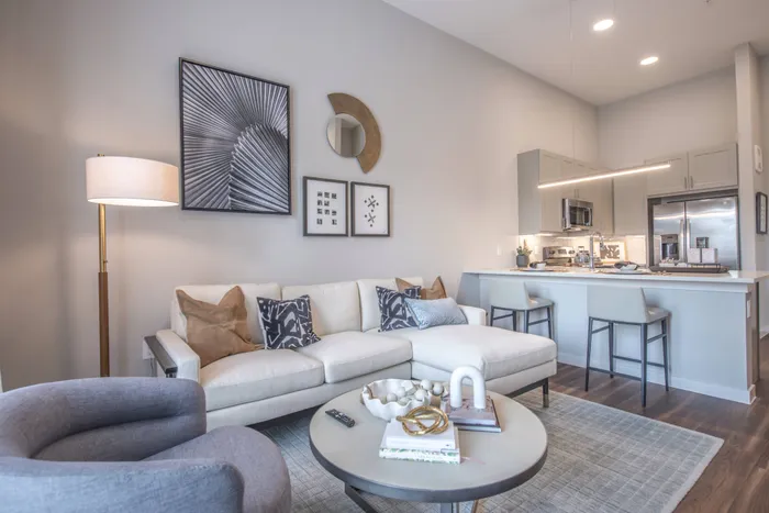 spacious room with white walls, a large window, white couch, a rug, and other living room furniture