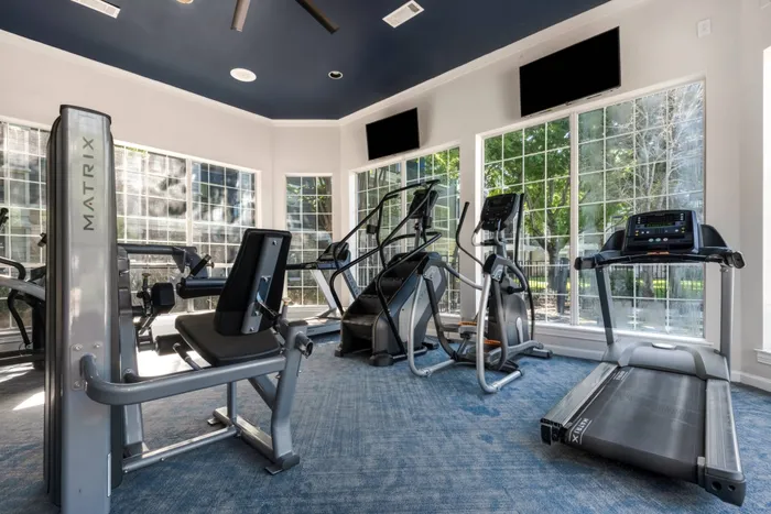 fitness center with televisions, exercise equipment, and large windows