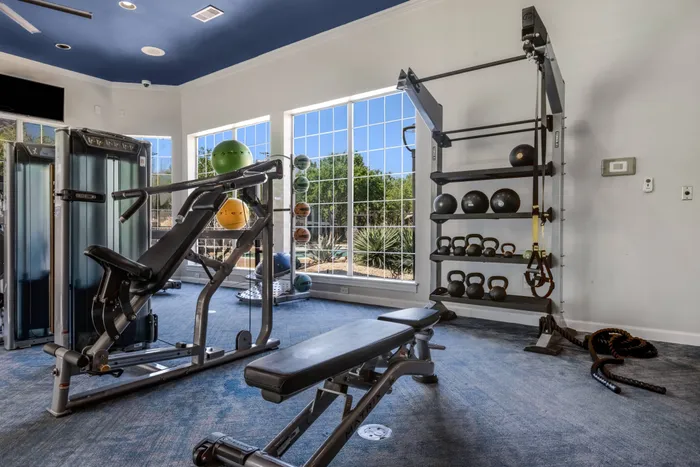fitness center with televisions, exercise equipment, and large windows