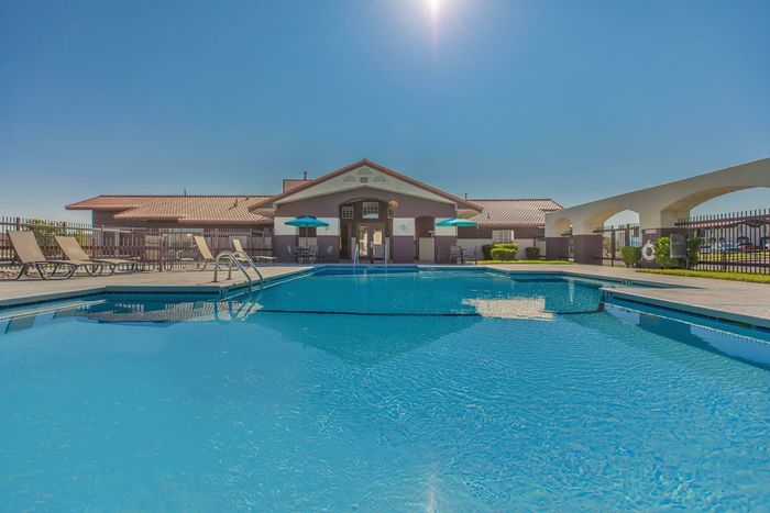 Outdoor pool with comfortable lounge chairs and shaded seating at Santa Teresa Terrace in Santa Teresa, NM.
