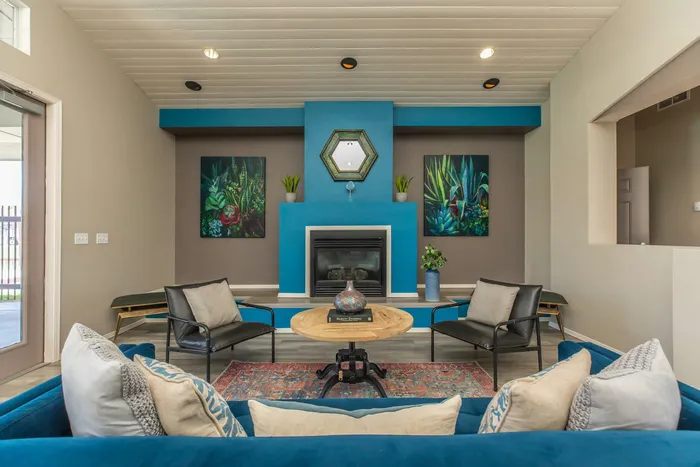 Modern community lounge with a vibrant blue fireplace and cozy seating at Santa Teresa Terrace in Santa Teresa, NM.