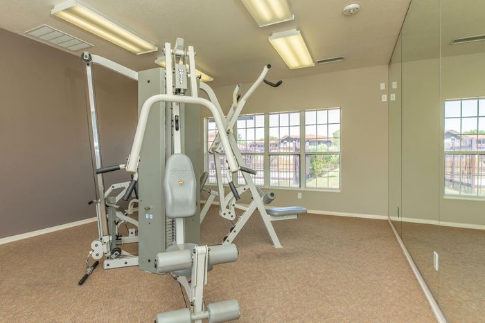 Fitness room with modern exercise equipment and mirrored walls at Santa Teresa Terrace in Santa Teresa, NM.