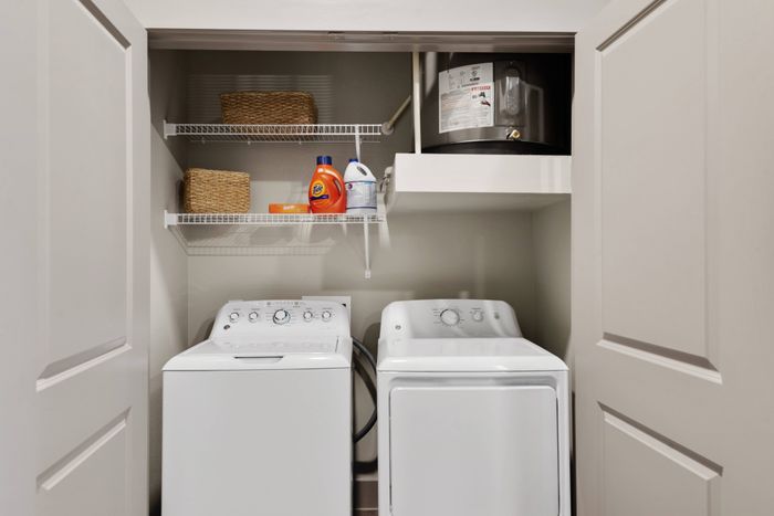 Compact washer and dryer closet with organized shelving at Discovery Park in Denton, Texas.