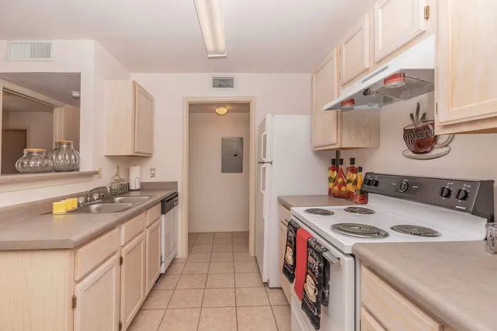 Kitchen with white appliances, tile flooring, and light wood cabinetry at Santa Teresa Terrace in Santa Teresa, NM.