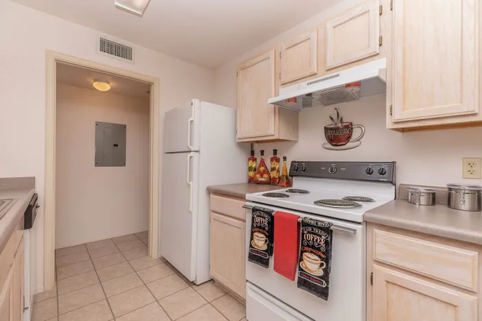 Kitchen with white appliances, tile flooring, and light wood cabinetry at Santa Teresa Terrace in Santa Teresa, NM.