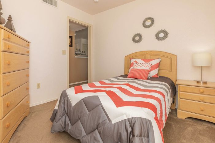 Bedroom with a red-themed bedspread, natural light, and warm decor at Santa Teresa Terrace in Santa Teresa, NM.