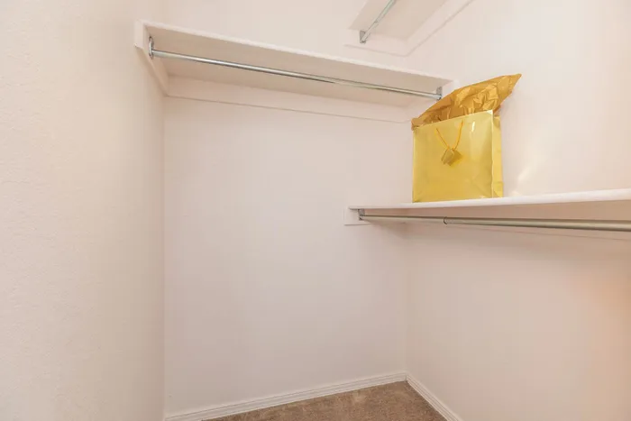 Spacious walk-in closet with built-in shelving and carpeted flooring at Santa Teresa Terrace in Santa Teresa, NM.