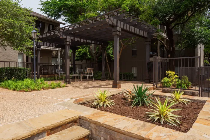 Inviting outdoor pergola at Oak Park Apartments in Euless, TX, with seating and lush landscaping for relaxation or gatherings.