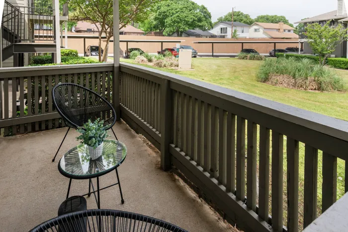 Private patio at Oak Park Apartments in Euless, TX, overlooking landscaped greenery with cozy seating.