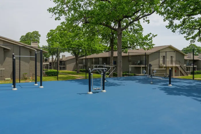 Outdoor fitness area at Oak Park Apartments in Euless, TX, with exercise equipment and a spacious layout.