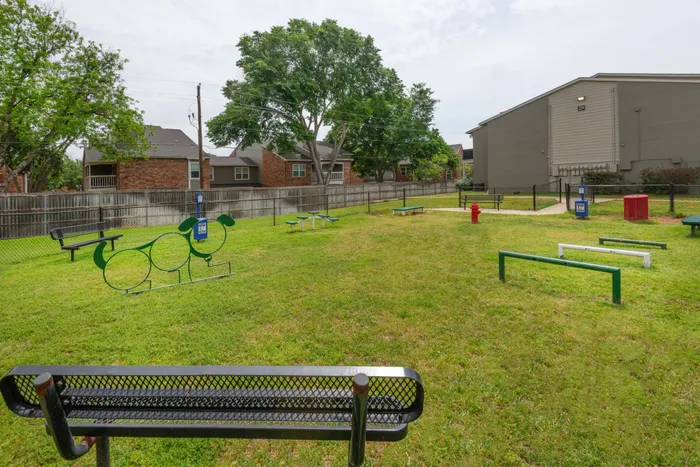 Spacious dog park at Oak Park Apartments in Euless, TX, with benches and open space for your furry friends to play.