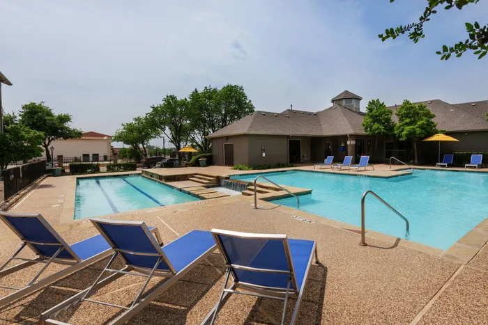 Resort-style swimming pool at Oak Park Apartments in Euless, TX, surrounded by lounge chairs and vibrant landscaping.