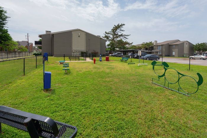 Spacious dog park at Oak Park Apartments in Euless, TX, with benches and open space for your furry friends to play.